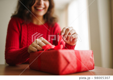 Female hands opening red gift box. Unpacking a gift. Valentines day celebration concept. Female hands opening red gift box. Unpacking a gift. Valentines day celebration concept. 98005307