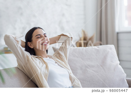 Young beautiful woman resting on sofa at home. She put her hands behind her head, closed her eyes. Young beautiful woman resting on sofa at home. She put her hands behind her head, closed her eyes. 98005447