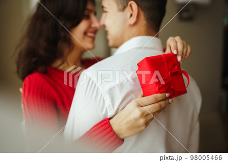 A young man gives his beloved a present and closes her eyes with a hand. 98005466