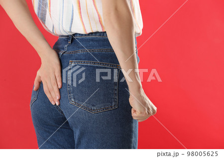 Woman suffering from hemorrhoid on red background, closeup Woman suffering from hemorrhoid on red background, closeup 98005625