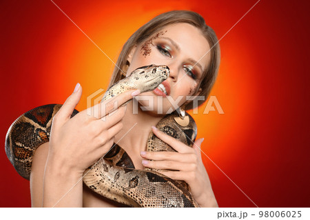 Beautiful woman with boa constrictor on bright colorful  background 98006025