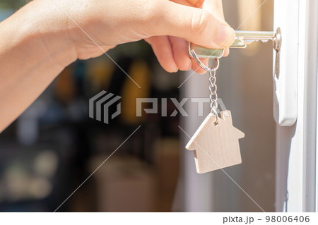 Opening door to a new home with key and home shaped keychain. Property and new home concept 98006406