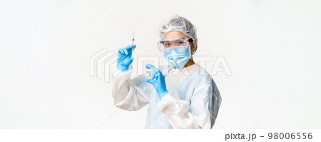 Asian doctor or nurse in medical protective equipment, looking confident at camera, holding syringe and vaccine from covid-19, vaccination campaign and medical concept Asian doctor or nurse in medical protective equipment, looking confident at camera, holding syringe and vaccine from covid-19, vaccination campaign and medical concept 98006556