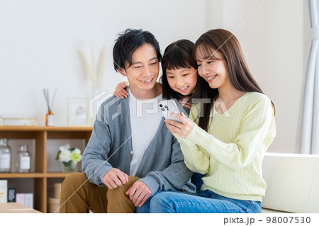 リビングでスマホを見る若い家族 98007530