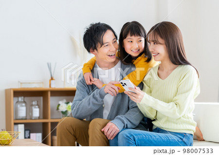 リビングでスマホを見る若い家族 98007533