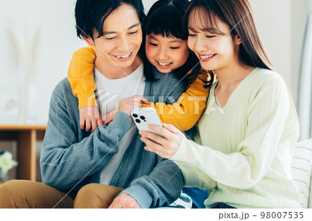 リビングでスマホを見る若い家族 98007535