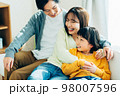 リビングでくつろぐ若い家族 98007596