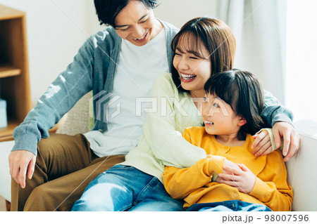 リビングでくつろぐ若い家族 98007596