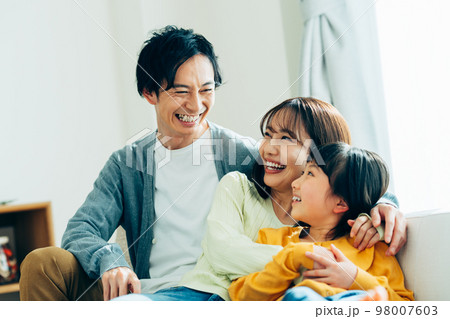 リビングでくつろぐ若い家族 98007603