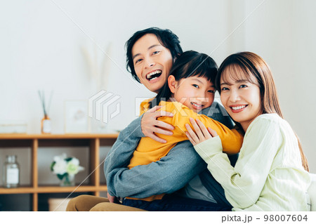 リビングでくつろぐ若い家族 98007604