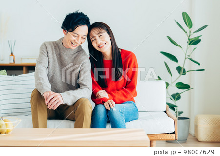 リビングで寛ぐ若い夫婦 98007629