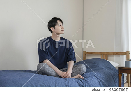 ベッドの上に座った若い男性 ベッドの上に座った若い男性 98007867