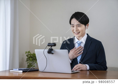ウェブカメラに向かって話すスーツ姿の若い男性　ウェブ会議　オンライン面接　イメージ 98008557