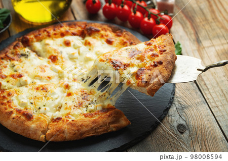 A slice of hot Italian pizza with stretching cheese. Pizza four cheeses with basil. 98008594