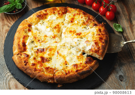 A slice of hot Italian pizza with stretching cheese. Pizza four cheeses with basil. 98008613