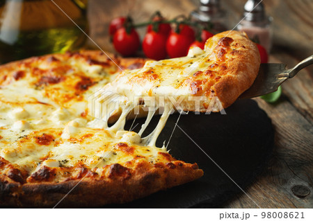 A slice of hot Italian pizza with stretching cheese. Pizza four cheeses with basil. 98008621