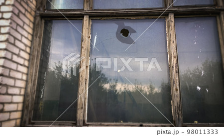 hole in the window pane of an old house. Glass broken by hooligans with a stone hole in the window pane of an old house. Glass broken by hooligans with a stone 98011333