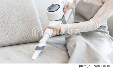 Woman vacuuming the floor of her living room, Big cleaning in the house, Removes germs and dirt and deep stains, Housewife cleaning, Keeping her home clean, Domestic hygiene. 98014630