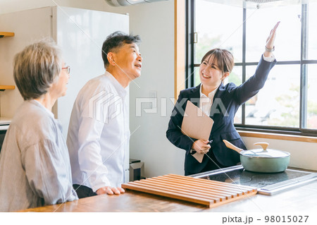住宅展示場・モデルルーム・ハウスメーカーで高齢者夫婦に説明するアジア人ビジネスウーマン 98015027
