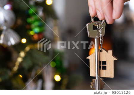 Key to the house with a keychain is hanging on the Christmas tree. A gift for New Year, Christmas. Building, design, project, moving to new house, mortgage, rent and purchase real estate. Copy space Key to the house with a keychain is hanging on the Christmas tree. A gift for New Year, Christmas. Building, design, project, moving to new house, mortgage, rent and purchase real estate. Copy space 98015126