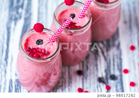 Top view of three tasty berries milkshakes made from raspberry, blueberries, currant in glass jars Top view of three tasty berries milkshakes made from raspberry, blueberries, currant in glass jars 98017282