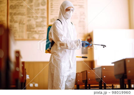Disinfecting of office to prevent COVID-19, Man in protective hazmat suit with with spray chemicals. Disinfecting of office to prevent COVID-19, Man in protective hazmat suit with with spray chemicals. 98019960
