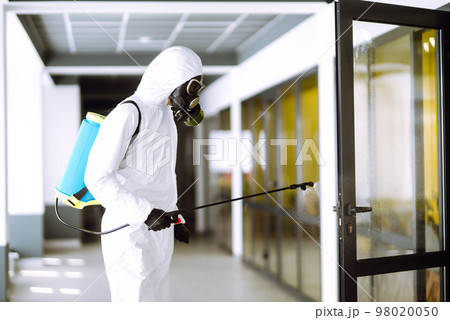 Disinfecting of office to prevent COVID-19, Man in protective hazmat suit with spray chemicals. Disinfecting of office to prevent COVID-19, Man in protective hazmat suit with spray chemicals. 98020050