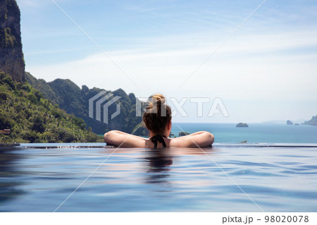 Woman Resting In Infinity Pool At a Aonang Beach Resort 98020078