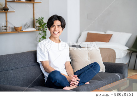 部屋でくつろぐ若い男性 98020251