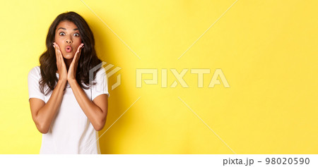 Portrait of attractive african-american teenage girl looking amazed, saying wow and stare at camera excited, standing over white background Portrait of attractive african-american teenage girl looking amazed, saying wow and stare at camera excited, standing over white background 98020590