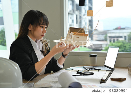 Architect woman working on design of a construction plan and examining construction plans at office 98020994