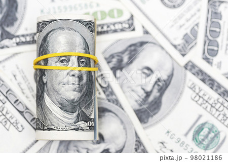 A roll of 100 dollar bills closeup on pile of American dollars. Background 98021186