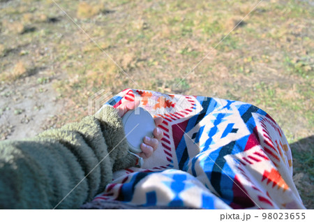 冬のキャンプで寒くてハンドウォーマー（充電式カイロ）で手を温める若い女性 98023655