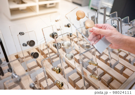 Male hand choosing cabinet door knob in furniture store 98024111