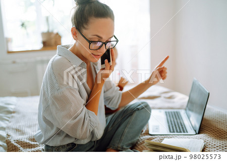 Young mother talking on the phone and discussing work issues while looking after her child. Covid-19. Young mother talking on the phone and discussing work issues while looking after her child. Covid-19. 98025573