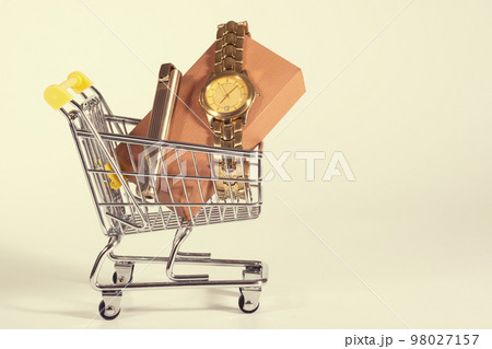 A golden watch in a shopping cart at the white background. Presents, purchases. A toned photo 98027157