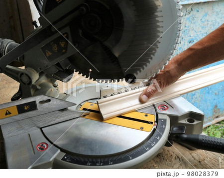 marking and cutting wooden planks on a miter saw, an angle saw in a carpenter's workshop while working with wood panels, trimming the ends of floor skirting boards on a miter saw 98028379