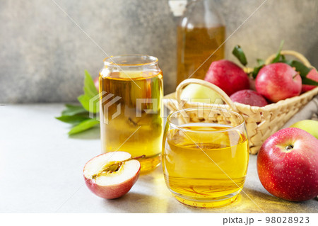 Autumn vitamin drink juice apple. Apple juice in a glass and fresh apples on a stone tabetop. Copy space. 98028923