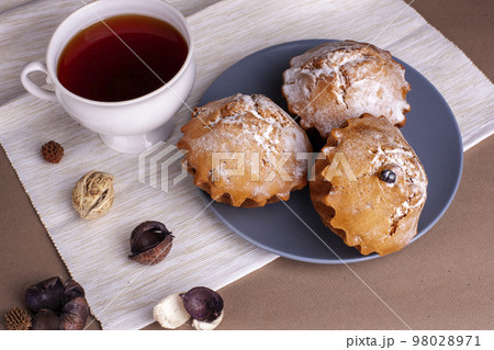 Pecan nut muffins with cup of tea on a plate. Grey background with cupcake. Pecan nut muffins with cup of tea on a plate. Grey background with cupcake. 98028971