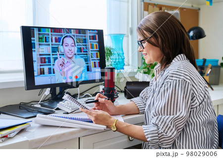 Mature woman talking online with teenage girl using video call 98029006