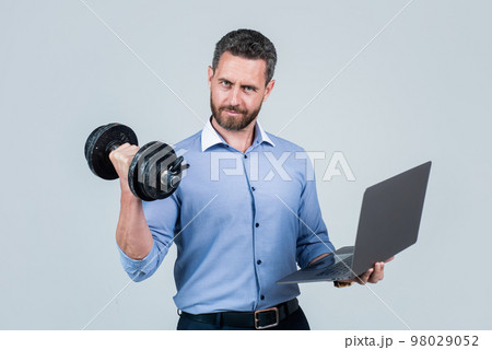 Online work gym that helps spur productivity. Manager hold laptop curling dumbell. Strength training. Business coach. Fitness at work. Weightlifting workout. Workplace gym. Technology in sport 98029052
