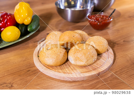 Freshly baked burger buns with sesame seeds in kitchen Freshly baked burger buns with sesame seeds in kitchen 98029638