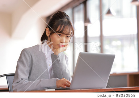 デスクワーク_頬杖をつき怒った顔でPCを睨み付ける女性_1 98030958