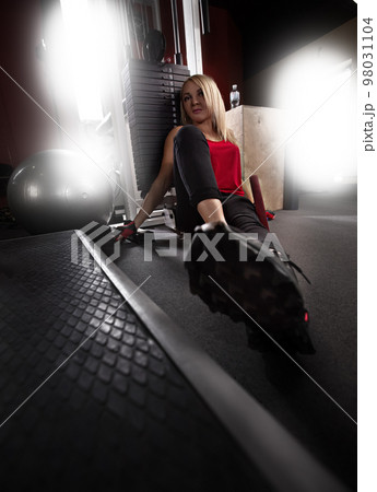 Attractive sporty woman relaxing with barbell in gym. Beautiful fitness girl resting after sport workout exercises. Rear view of female in sportswear with perfect body posing in the gym.beautiful girl Attractive sporty woman relaxing with barbell in gym. Beautiful fitness girl resting after sport workout exercises. Rear view of female in sportswear with perfect body posing in the gym.beautiful girl 98031104