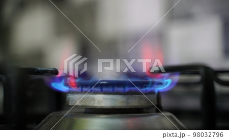 Kitchen burner turning on. Stove top burner igniting into a blue cooking flame. Kitchen burner turning on. Stove top burner igniting into a blue cooking flame. 98032796
