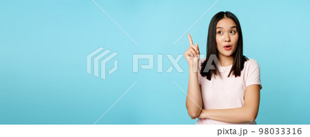Eureka. Young asian woman found solution. Korean girl raising finger up and pitching an idea, standing thoughtful over blue background 98033316