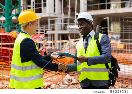 Successful architect and engineer shake hands on construction site 98033555