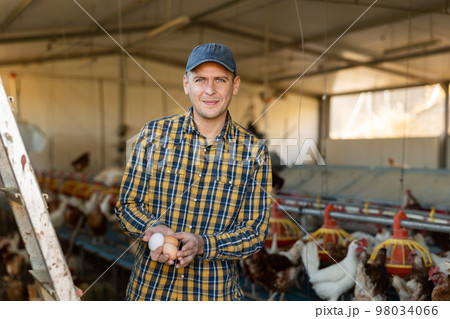Portrait of man farmer holding eggs in hands in henhouse 98034066