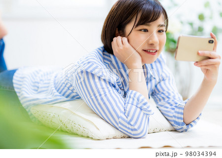 女性が寝ながらスマホを見る 女性が寝ながらスマホを見る 98034394