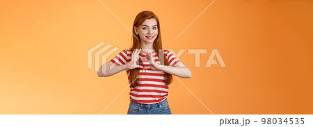 Cute lovely cheerful redhead girlfriend express love and cherish relationship, celebrating anniversary show heart sign, smiling tenderly, confess sympathy, stand orange background 98034535